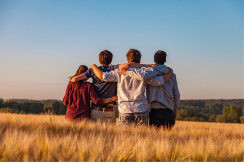 A group of people facing away from the camera, arms around each other.